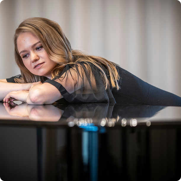 Pianist leaning on piano with reflective surface