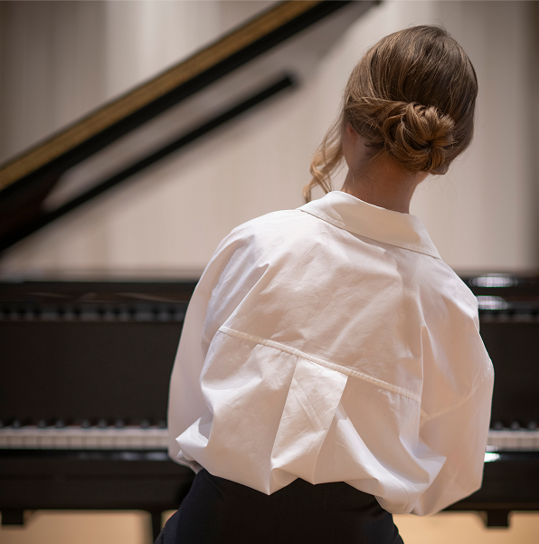 Young girl sitting at a piano, viewed from behind